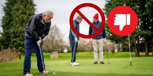 Golfers talking during another golfer putting
